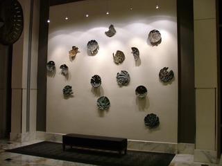 Wall with abstract ceramic sculptures and a bench below.