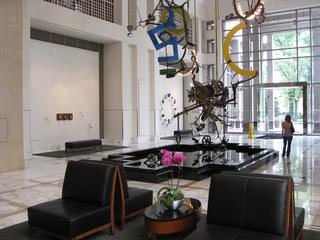 Modern building interior with a hanging metal sculpture and a seating area with orchids.