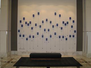 Art installation with blue rectangles on a white wall.