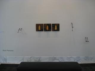 Art installation of three ceramic bottels and spoons on a wall.