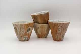 a set of 4 Woodfired Wine Cups in earthtones with light blue white interiors.  The cups are staged against a white background.