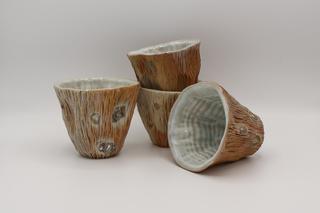 a set of 4 Woodfired Wine Cups in earthtones with light blue white interiors.  The cups are staged against a white background.