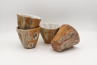 a set of 4 Woodfired Wine Cups in earthtones with light blue white interiors.  The cups are staged against a white background.